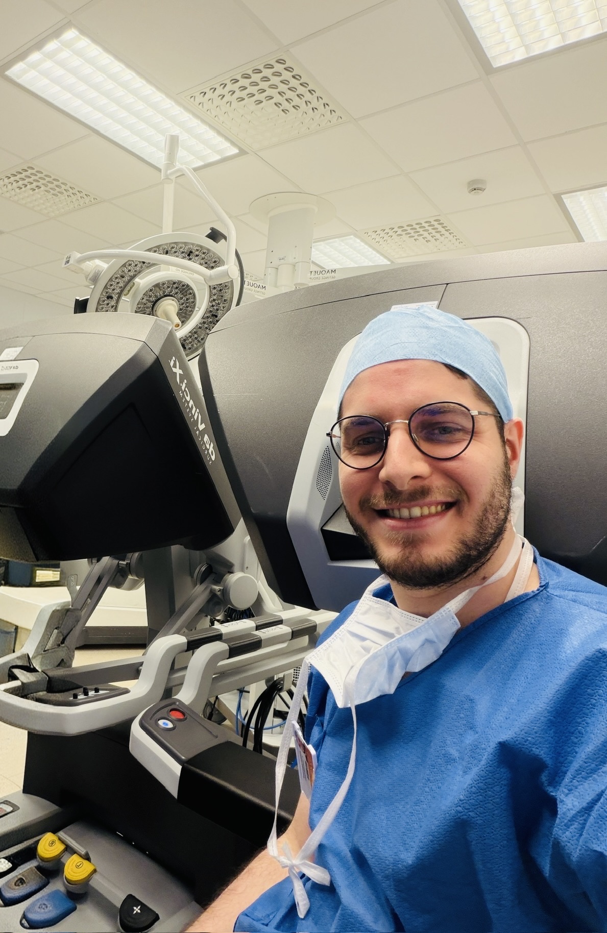 Abdullah Harun Kınık, MD, smiling at the robotic surgery console in surgical attire